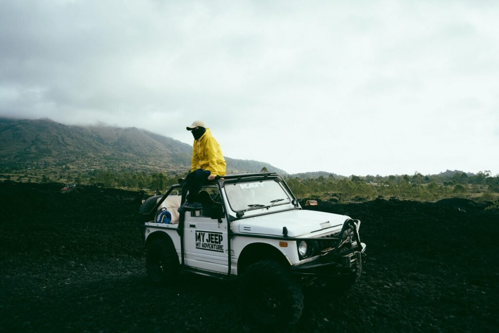 Jeep and visitor on black lava terrain below Mount Batur, Bali