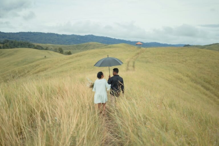 A couple walking through the grass-covered Teletubbies Hills in Tanglad, Nusa Penida.
