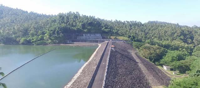 Benel Reservoir water and dam embankment, with green hills in Jembrana, Bali.