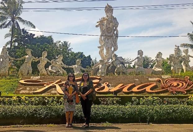 Krisna Blangsinga sign and statue garden with two visitors in front