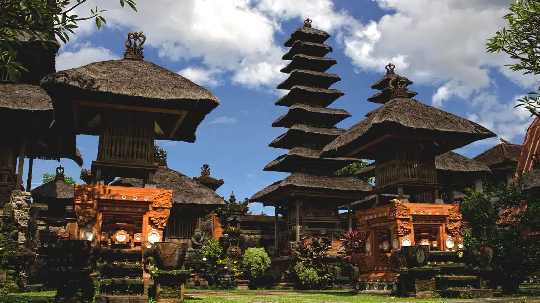 Traditional multi-tiered roofs of Kesiman Palace against a blue sky in Bali.