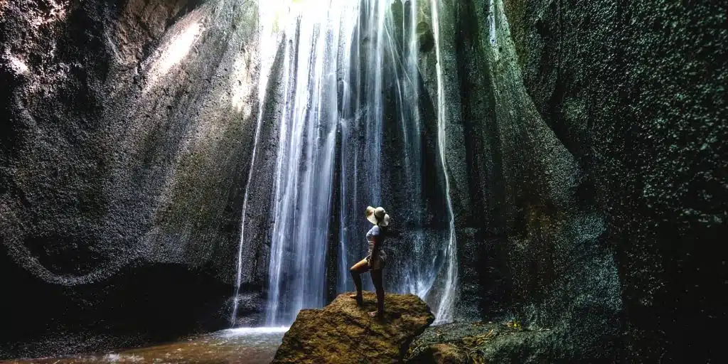 A solitary figure bathed in light at Tukad Cepung Waterfall.